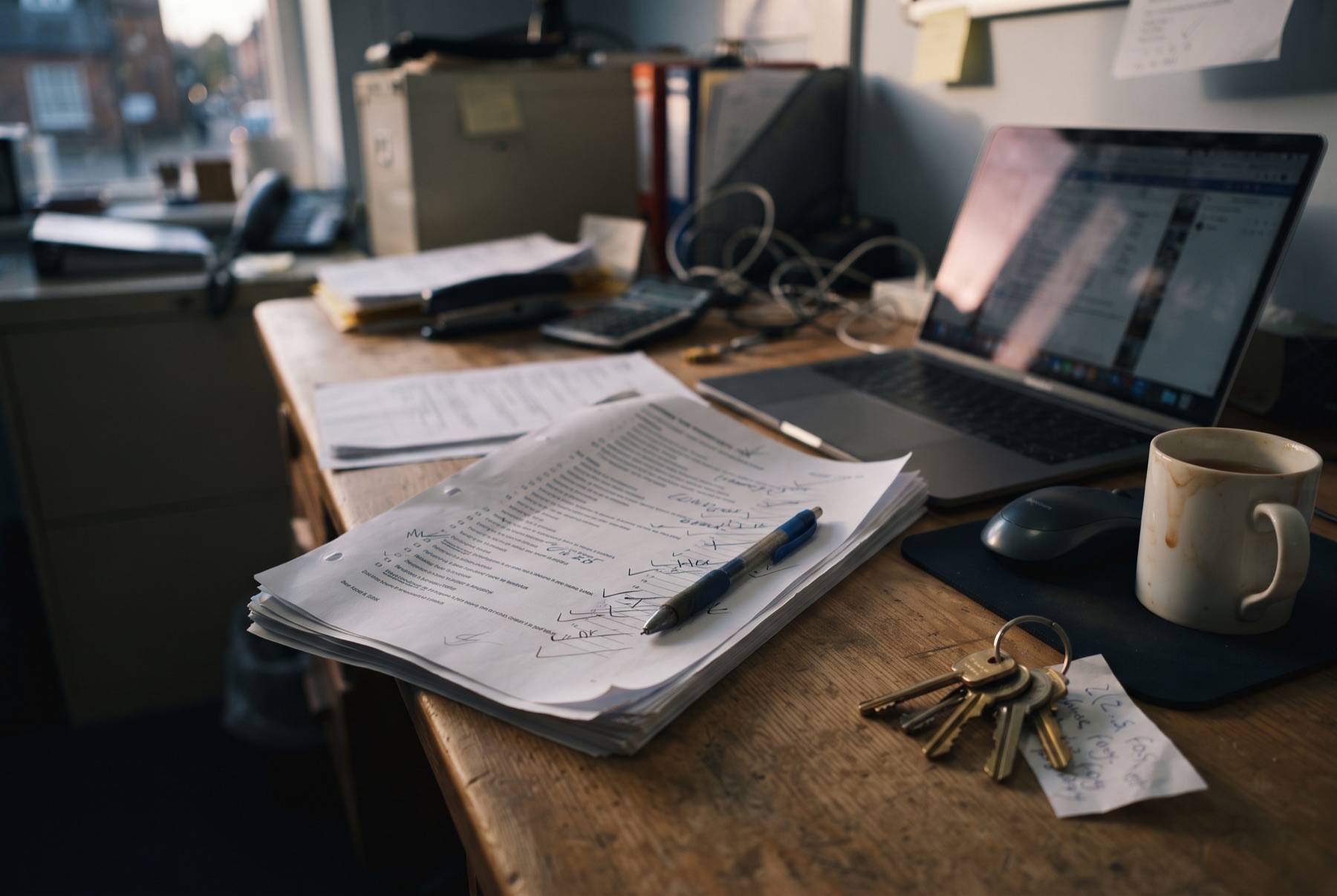 A letting agent's desk at the end of the day, a half-finished inventory beside a cold mug of tea