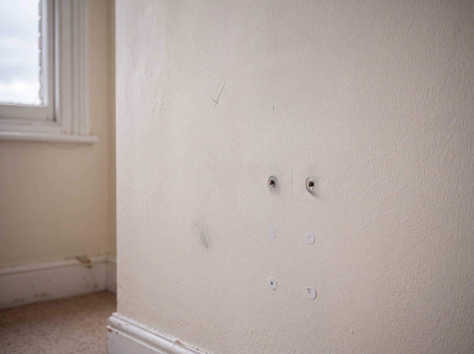 Picture hook holes on a magnolia wall